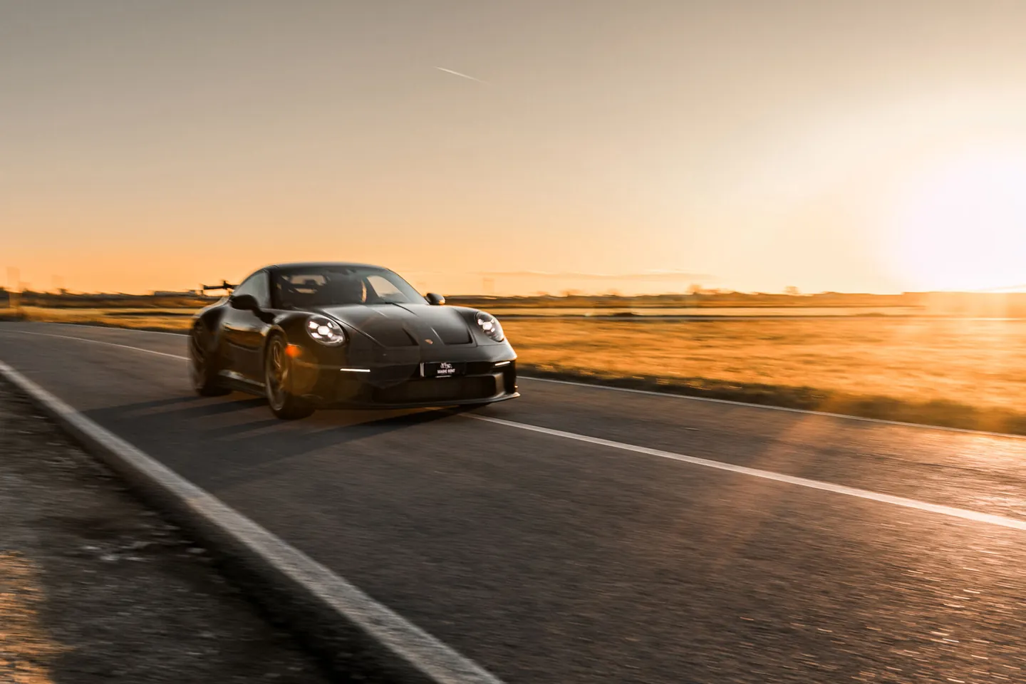 Porsche nera su una strada al tramonto