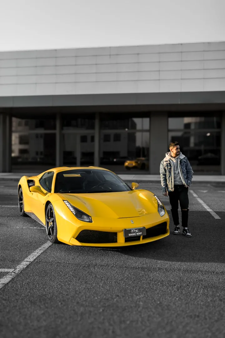 Ferrari gialla scoperta con una persona accanto, davanti a un edificio