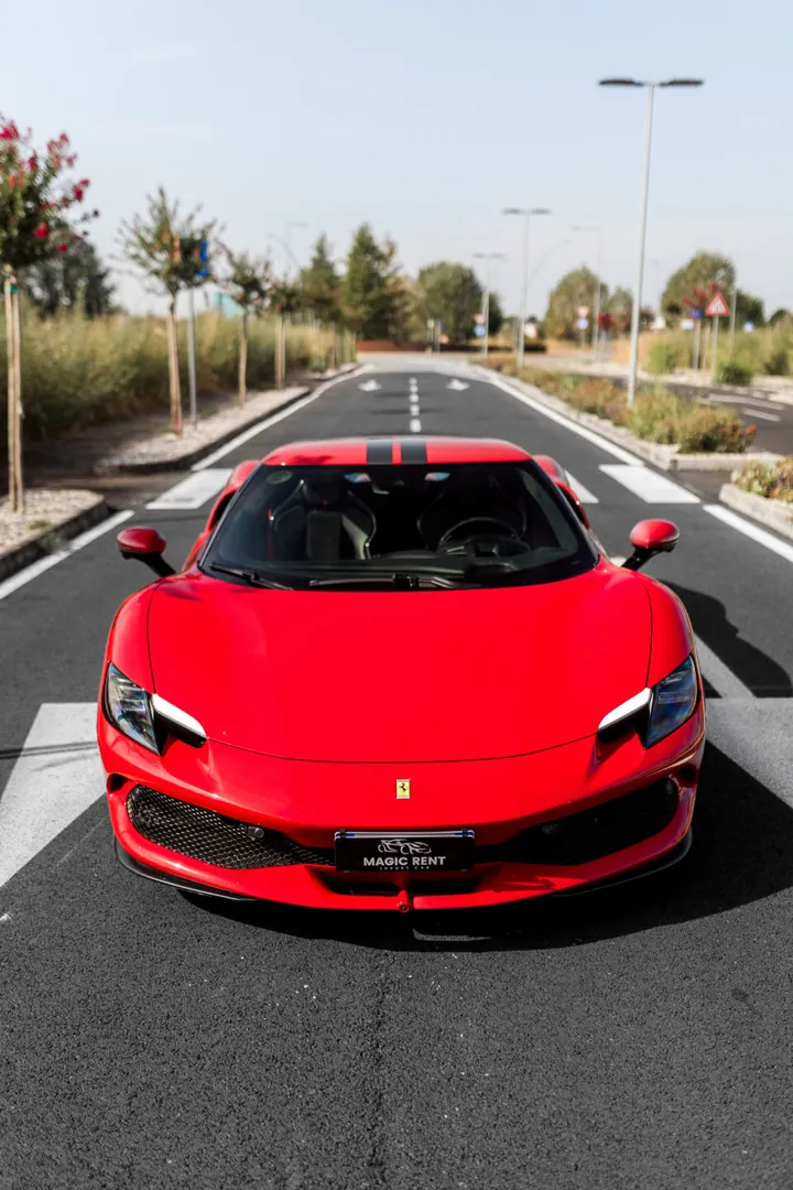 Ferrari rossa vista di fronte, su una strada con la segnaletica a terra