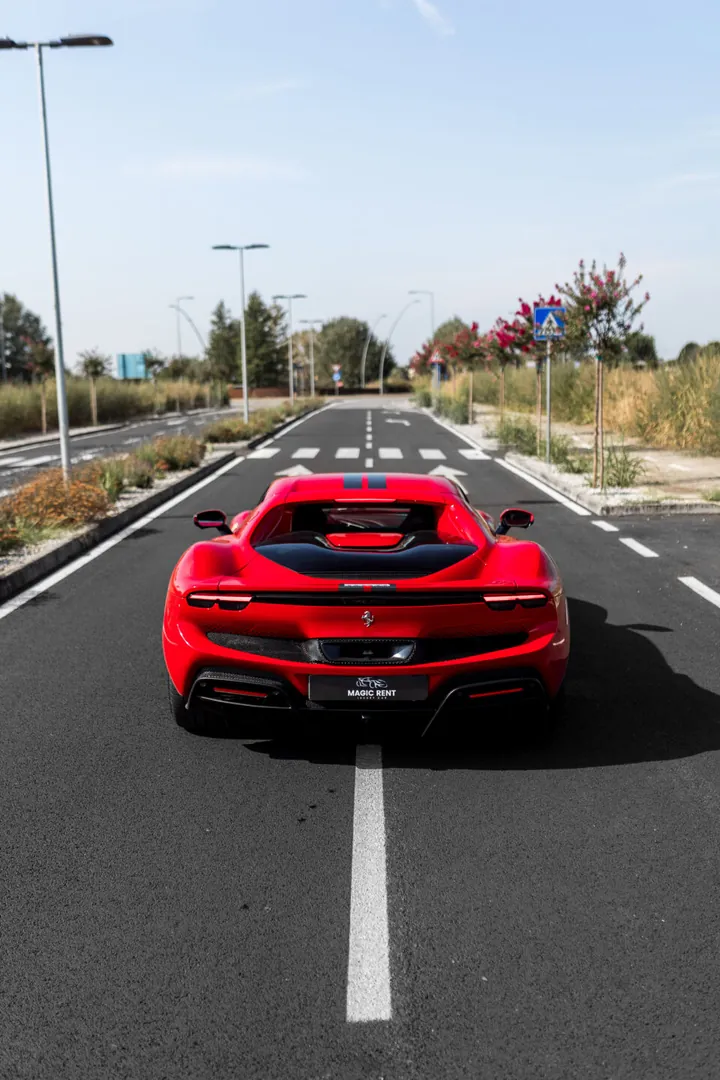Ferrari rossa vista da dietro, al centro della strada